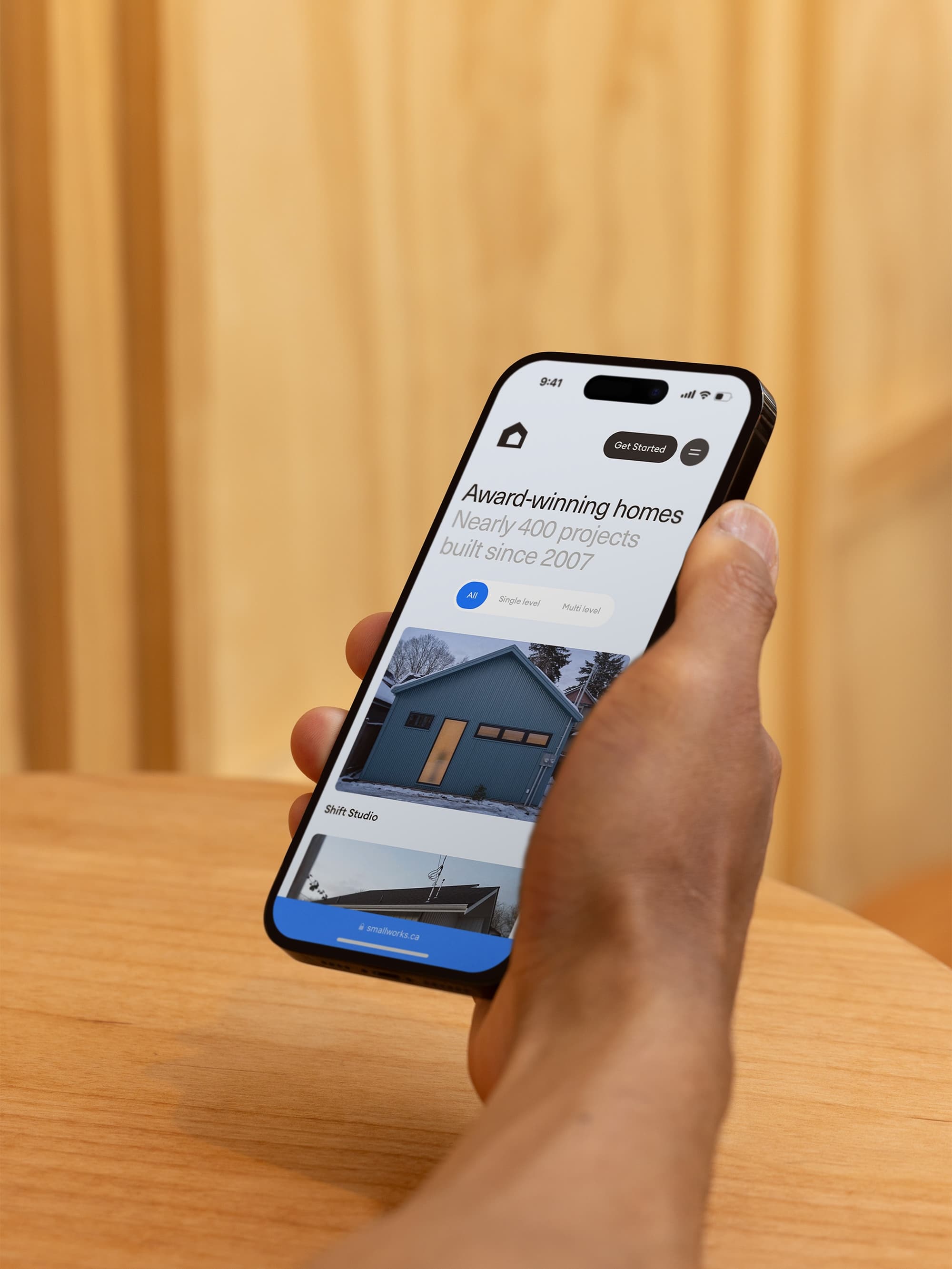 Person holding a smartphone with the Smallworks website on the screen